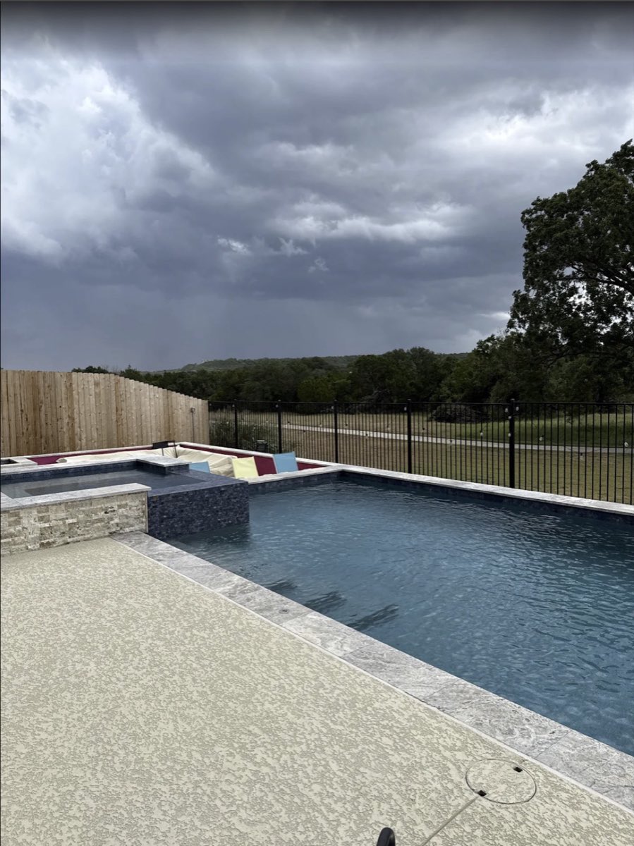 Rectangular pool and spa with travertine deck and Texas Hill Country view, built and serviced by Endless Blue Pools near Round Rock, TX